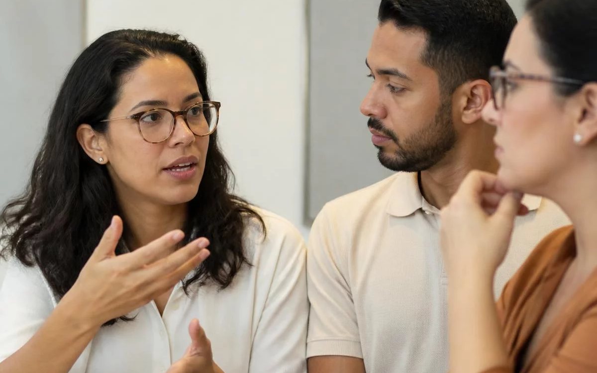 Roda de conversa numa sala clara, com uma pessoa expondo o ponto e duas escutando